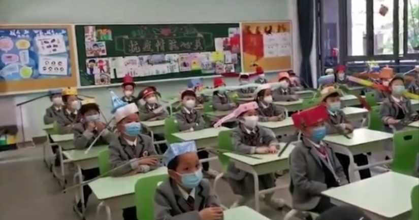 Niños chinos Van a la Escuela con Sombreros Divertidos para Distanciarse Socialmente