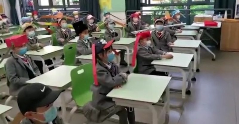 Niños chinos Van a la Escuela con Sombreros Divertidos para Distanciarse Socialmente