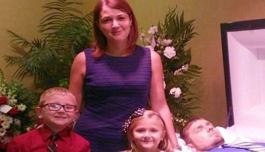 That's why this woman with children is smiling near her husband's coffin