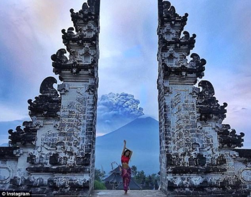 While the residents of Bali are moving away from the volcano, tourists are photographed against the background of ash emissions