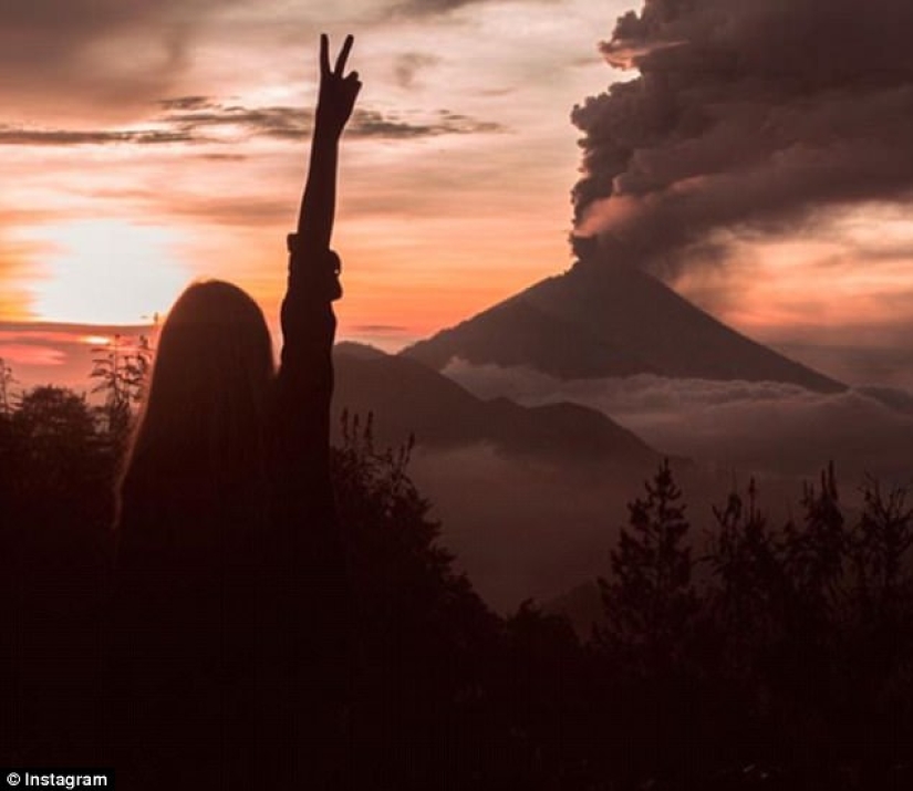 While the residents of Bali are moving away from the volcano, tourists are photographed against the background of ash emissions