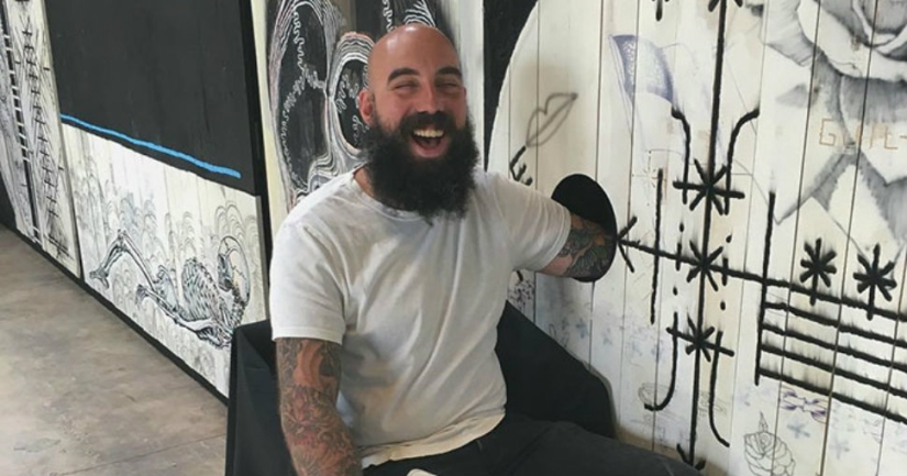 A hole with a surprise: the master offers to make people a tattoo for free if they put their hand in the hole