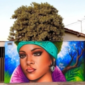 Artista callejero continúa pintando retratos en paredes junto a árboles que también sirven como cabello