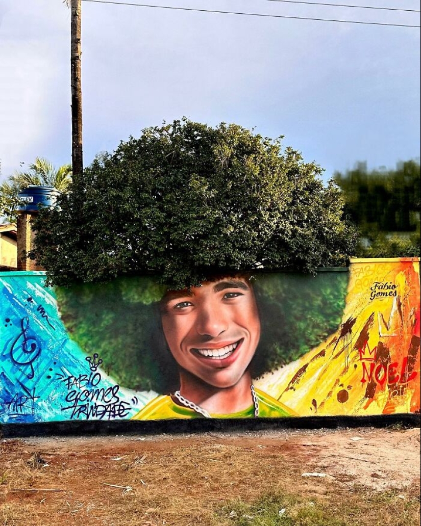 Street Artist Continues To Paint Portraits On Walls Next To Trees That Double As Hair