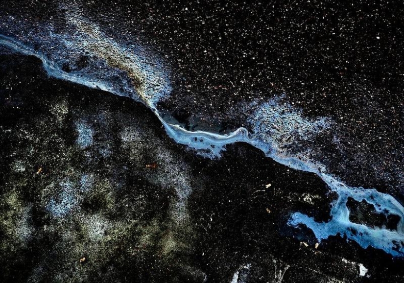 Galaxias y constelaciones ilusorias hechas de gasolina y aceite sobre asfalto
