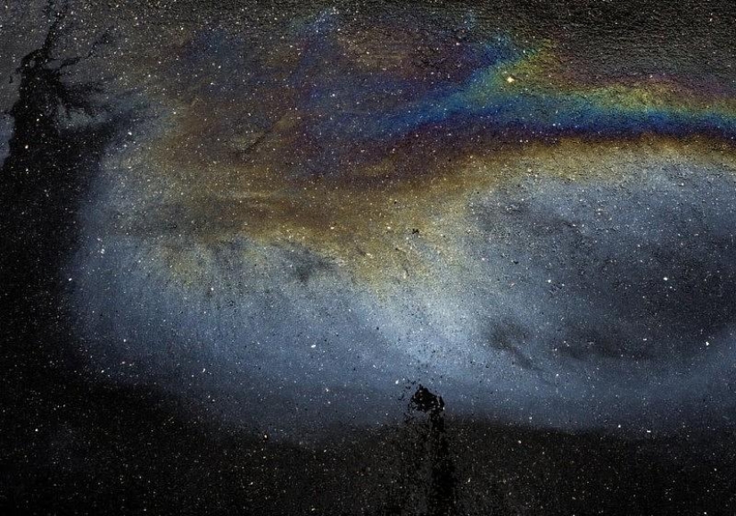 Galaxias y constelaciones ilusorias hechas de gasolina y aceite sobre asfalto
