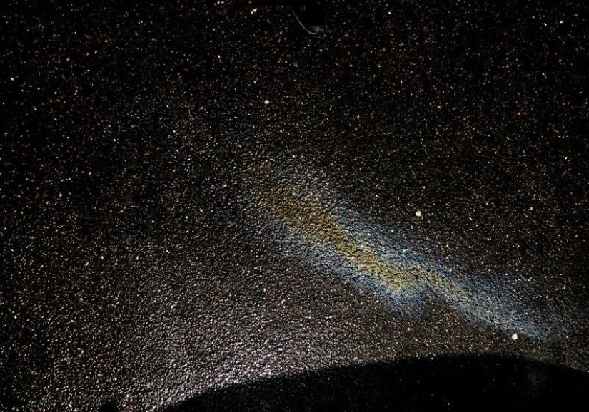 Illusory galaxies and constellations made of gasoline and oil on asphalt