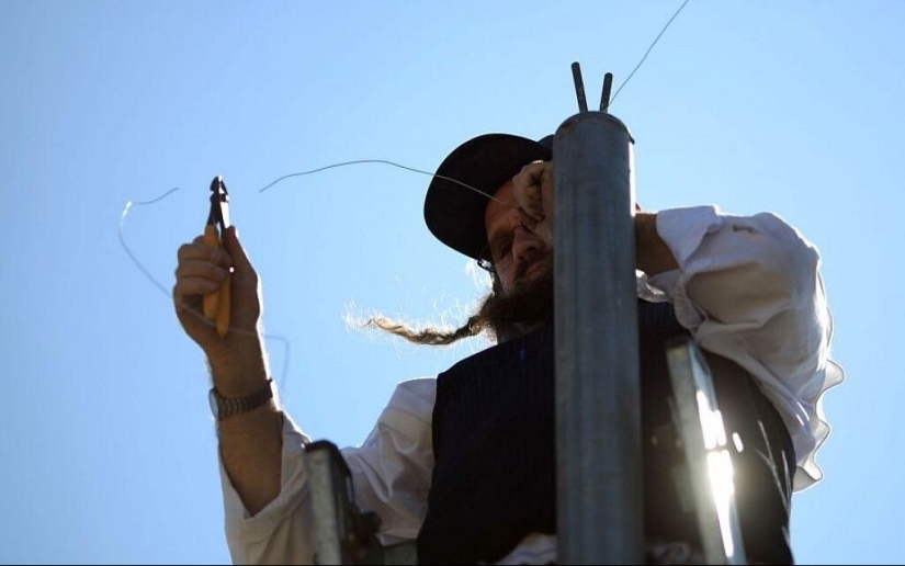 Why do Jews stretch kilometers of fishing line over cities around the world?