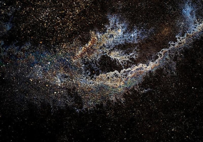 Illusory galaxies and constellations made of gasoline and oil on asphalt