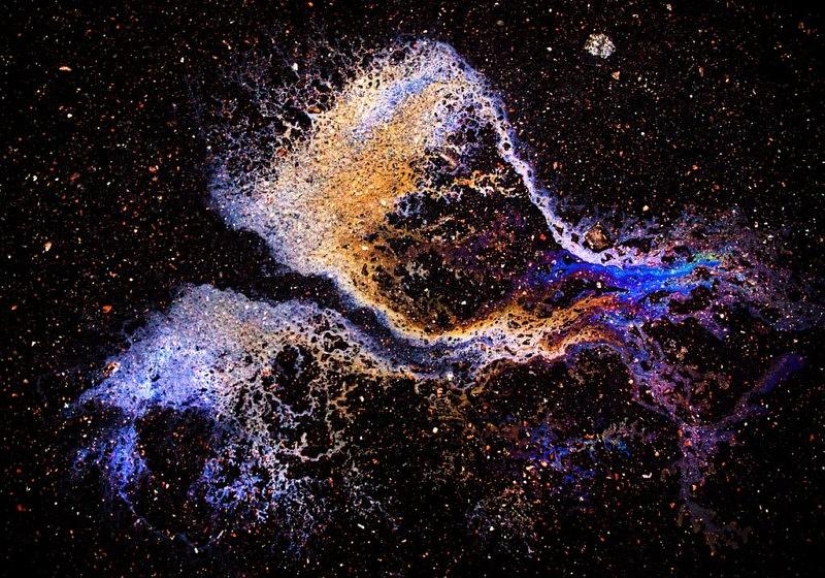 Illusory galaxies and constellations made of gasoline and oil on asphalt