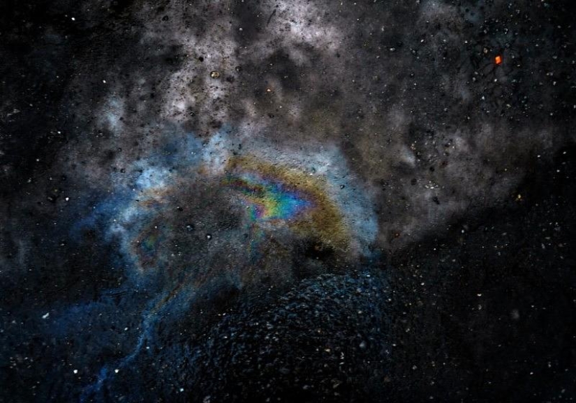 Illusory galaxies and constellations made of gasoline and oil on asphalt