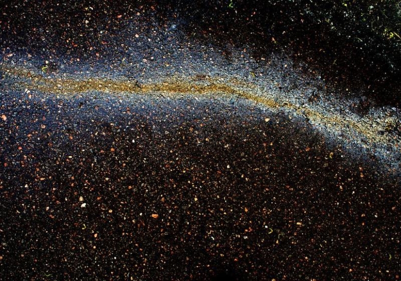 Illusory galaxies and constellations made of gasoline and oil on asphalt