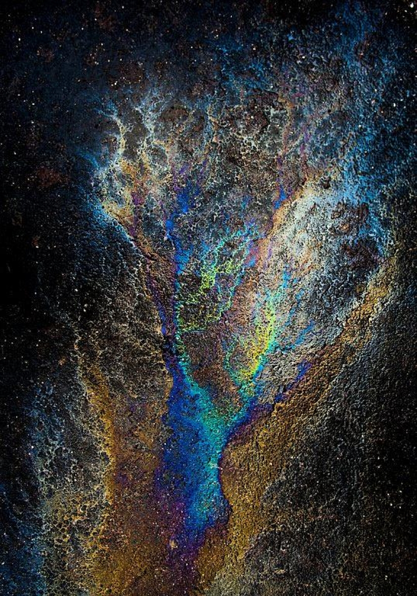 Illusory galaxies and constellations made of gasoline and oil on asphalt