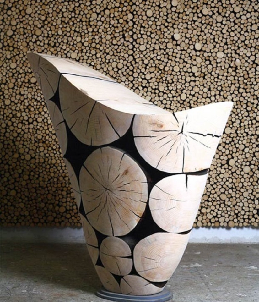 There is grass in the yard, firewood on the grass