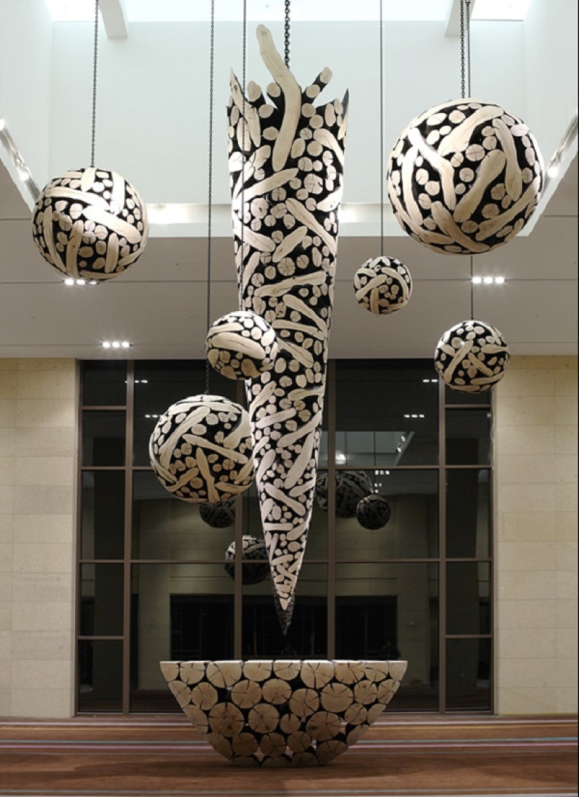 There is grass in the yard, firewood on the grass